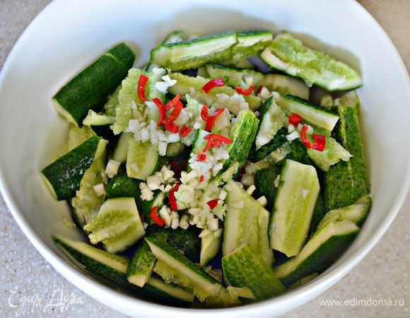 Срежьте с огурцов хвостики и нарежьте на небольшие куски примерно 2*4 см. Добавьте мелко рубленый чеснок, а также нарезанный мелко перец чили (предварительно не забудьте аккуратно, с помощью ножа, вынуть из него все семена). Потребуется маленький перчик или небольшой кусок от крупного перца.
