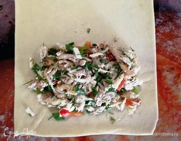 Шарик раскатываем в очень тонкий прямоугольник. На один край кладем щедрую порцию начинки.