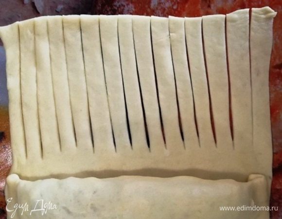 Подвернем тесто с начинкой еще раз. Свободный край часто нарежем. И просто сворачиваем заготовку рулетиком.