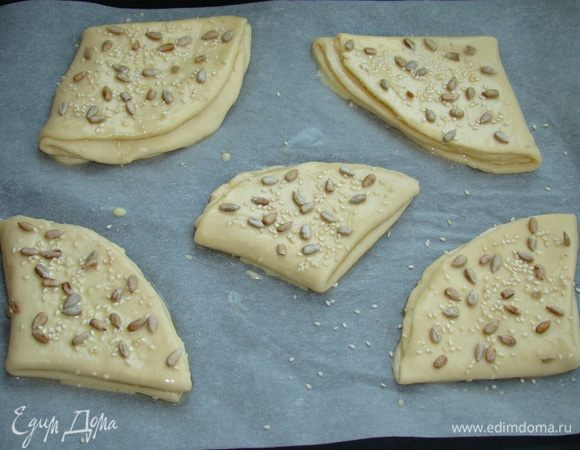 Таким образом раскатываем по 5 «кармашков» и, уложив на противень, смазать смесью яйца и ложки молока. Сверху посыпать семечками подсолнечника и кунжута (или кому что нравится). Выпекать в разогретой до 180°C духовке до румяного цвета, примерно минут 20.