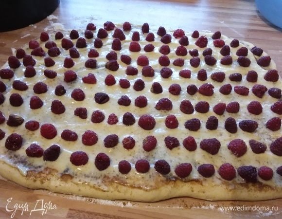 Затем распределить по всей поверхности полностью остывший крем и разложить малину рядами.