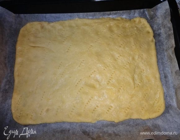 Противень застелить бумагой для выпечки. С помощью скалки аккуратно перенести пласт теста на противень. Наколоть вилкой в разных местах по всему периметру.