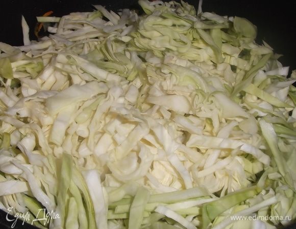 Так же в казан выложить нашинкованную капусту. Блюдо перемешать. Под крышкой тушить 10 минут.