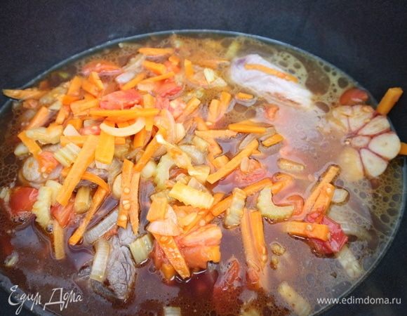 Добавить овощи, изюм, закрыть жаровню крышкой и тушить 2,5 часа. Через 15 минут вынуть половину головки чеснока, ее можно использовать для украшения блюда. За час до окончания приготовления, к этому времени соус загустеет, добавить соль, веточку розмарина. Тушить до готовности. Несколько раз нужно проверить мясо, перемешать, если потребуется, добавить немного бульона.