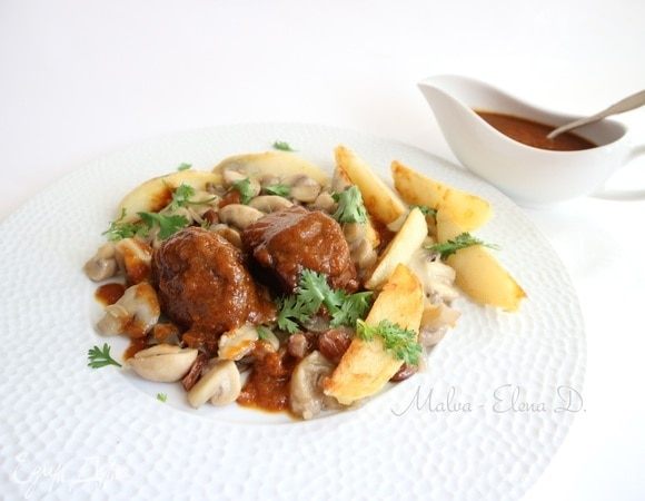 На тарелку положить шампиньоны, на них кусочки мяса, полить соусом, рядом дольки картофеля. Посыпать измельченной кинзой. Отдельно в соуснике подать соус.