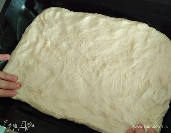 Расстоявшееся тесто аккуратно перевалить на противень, не обминать, а аккуратно растянуть пальцами.