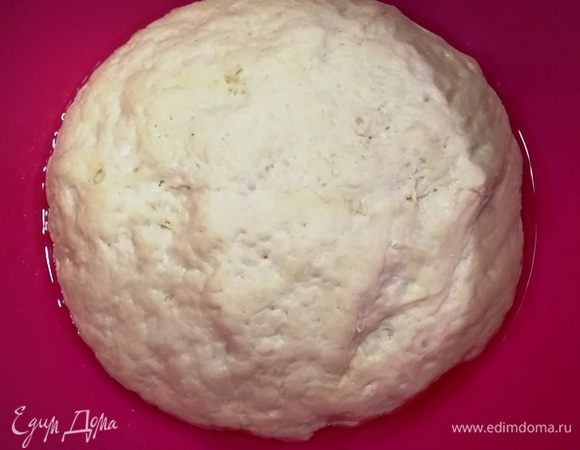 Прошло 30 минут, и тесто достаточно подросло. Обминаем его прямо в миске. На дне масло, поэтому тесто не будет липнуть к рукам. Да и отдохнувшее оно гораздо послушнее.