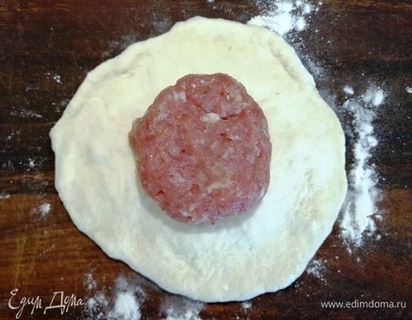 Ручками (никаких скалок, тесто любит тепло рук) растягиваем заготовку от центра к середине. Центр должен быть чуток пухлее краев. Кладем мясной шарик и слегка придавливаем его.
