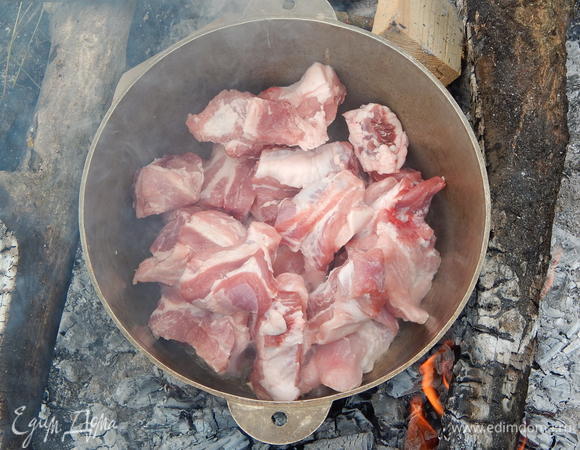 Свиные ребрышки моем и обсушиваем. Казан с маслом нагреваем на костре, добавляем ребрышки.