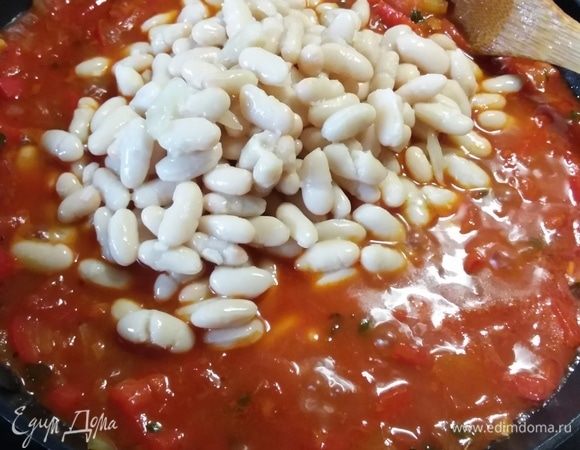 Духовку разогреть до 200°C. В соус выложить фасоль, влить 400 мл отвара или воды и отправить в духовку на 45 минут. Фасоль впитает всю жидкость и станет мягкой, нежной и насыщенной всеми вкусами и ароматами.