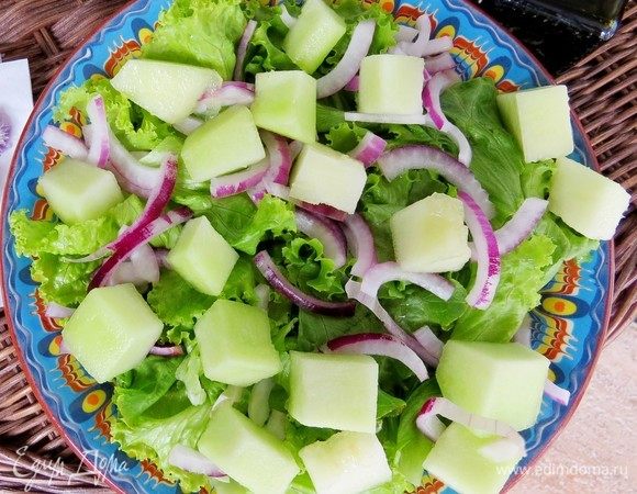 Дыню также нарезать кубиками и равномерно выложить на листья салата.