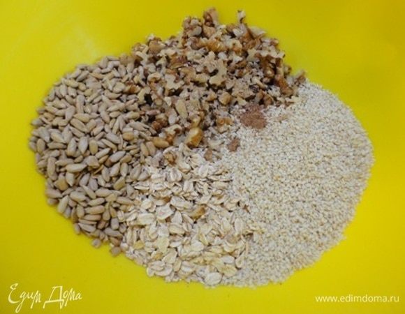 Духовку включить для разогрева на 150°C вместо указанных 170°C. Возможно, у меня духовка сильно нагревает, но при 170°C я сократила время, и у меня даже некоторые ягоды изюма подпеклись, и я их позже удалила. Соединить овсяные хлопья с семечками, орехами (у меня грецкие, нарезанные), сахаром и пряностями. Все перемешиваем.