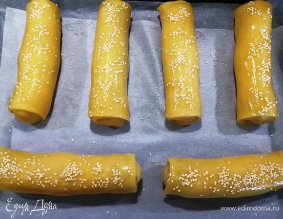 Выкладываем все заготовки на противень, смазываем яйцом и посыпаем кунжутом.