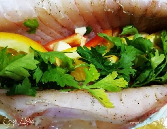 Рыбу солим и перчим внутри и снаружи. В брюшко укладываем несколько долек лимона, дольку апельсина, немного болгарского перца и помидора, петрушку.