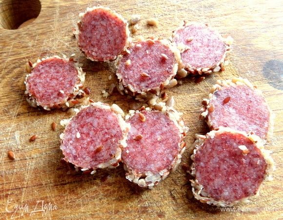Колбаску делим на кружочки. У меня — в панировке из семечек.