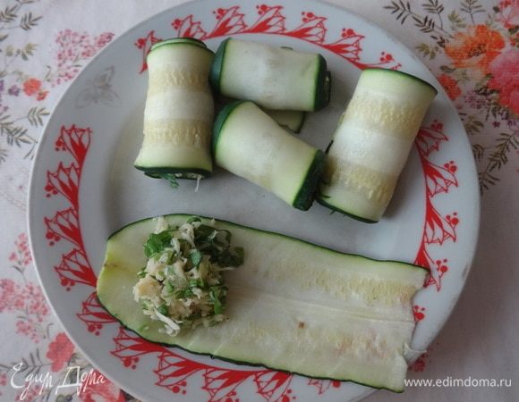 На край каждой остывшей пластинки цукини выкладывать по 1 ч. л. (или меньше) сырной начинки и сворачивать в рулетики.