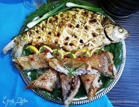 Подаем рыбу с дольками лимона и свежими овощами. Фотография размер не передает, диаметр подноса — 45 см. Рыба очень крупная, хватит на компанию.
