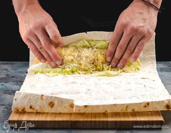 Последнюю полоску сформируйте из тертого сыра. Сверните лаваш с начинкой в плотный рулет, заверните его в пищевую пленку и уберите на 2 часа в холодильник.