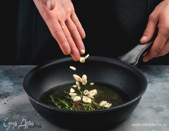 Чеснок нарежьте пластинками. В сковороде разогрейте оливковое масло, положите веточки розмарина и тимьяна. Далее добавьте чеснок и обжарьте 1 минуту.<br />
 