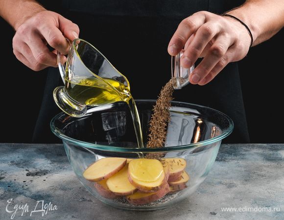 В емкости соедините оливковое масло, соль, перец, тмин. Замаринуйте картофель на 15 минут.<br />
 