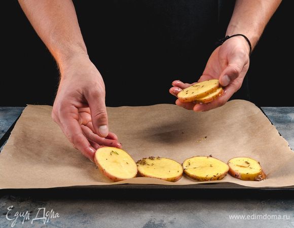 Противень выстелите пергаментом, выложите на него кружочки картофеля. Запекайте в заранее разогретой до 200°С духовке 15 минут.<br />
 