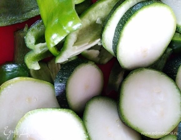 Молодые цукини вымыть и нарезать колечками толщиной около 0,5–0,7 см. Перец почистить и нарезать кусочками. Если взять перец желтый, то салат будет наряднее. Посолить и присыпать смесью перца. Сбрызнуть растительным маслом.