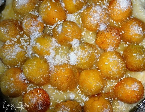 Пространство между абрикосами посыпать сахаром. Сливочное масло растопить и полить им поверх сахара и абрикосов. Посыпать весь пирог кунжутом. Поставить форму с пирогом в духовку, разогретую до 180°C и выпекать 30–35 минут. Готовый пирог аккуратно вынуть из формы и выложить на блюдо.