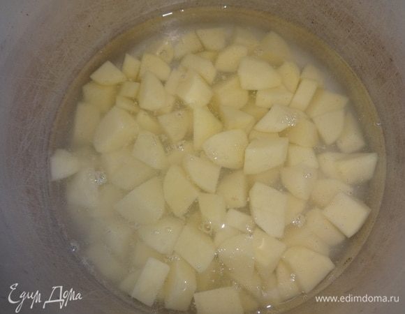 В кастрюлю налить воды. Довести до кипения, положить картофель. Снова дать закипеть, немного посолить. Убавить огонь и варить до полуготовности.