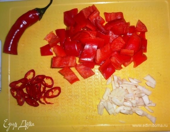 Из сладкого перца удалить семена, нарезать его небольшими кусочками. Острый красный перец нарезать тонкими колечками. Чеснок очистить и нарезать тонкой соломкой.