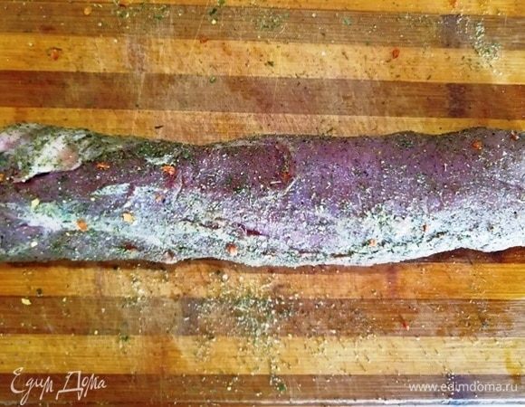 Прокатываем вырезку по специям, хорошо прижимая ее к доске.