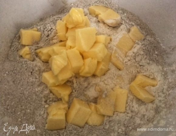 Просеять муку с пекарским порошком и нарезать кусочками масло комнатной температуры. Растереть.