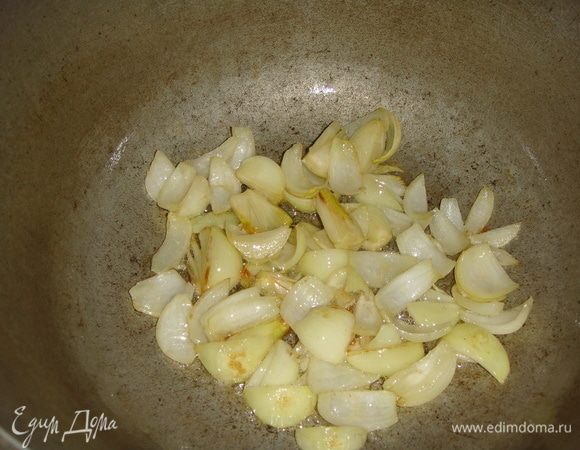 В большом казане разогреваем растительное масло и слегка обжариваем лук с чесноком.
