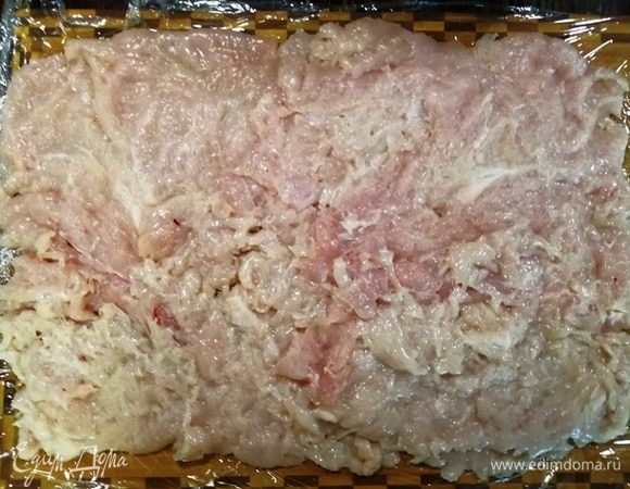 Большую разделочную доску накрываем пищевой пленкой. Пленку смазываем растительным маслом. Выкладываем филе в форме прямоугольника.