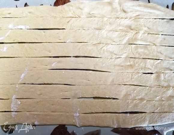 Средний кусочек раскатываем тонко в форме прямоугольника. Нарезаем длинные полоски шириной около 2–2,5 см.