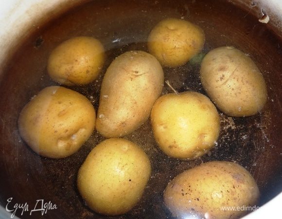 Картофель вымыть, не очищая, положить в горячую воду. Довести до кипения, посолить, убавить огонь и варить до готовности. Слить с картофеля воду, остудить.