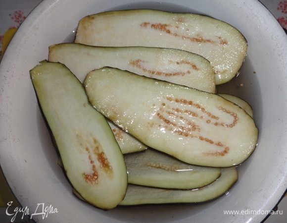 Положить пластины в холодную соленую воду на 15–20 минут. Сверху можно положить небольшой груз в виде тарелки, чтобы баклажаны полностью были погружены в воду.