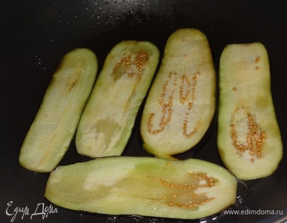 По истечении времени пластины баклажанов вынуть из воды, обсушить. В сковородку налить растительное масло, разогреть. Положить пластины баклажанов и обжаривать сначала с одной стороны до золотистого цвета.