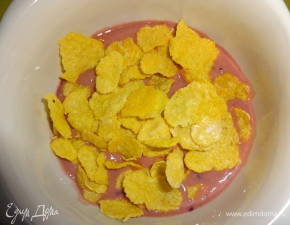 Отложить немного кукурузных хлопьев для украшения. В чашку влить 1/4 смузи, выложить половину хлопьев и сверху вылить еще 1/4 часть. Вторую порцию сделать аналогично. Украсить отложенными ягодами терна, хлопьями, абрикосом.