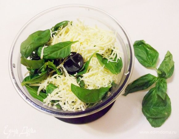 Приготовить соус песто. Соединить и измельчить блендером листья базилика, грецкие орехи, тертый пармезан, чеснок и оливковое масло до однородного состояния. Попробовать. Добавить по вкусу соль и черный молотый перец и еще раз взбить блендером. Соус песто готов.