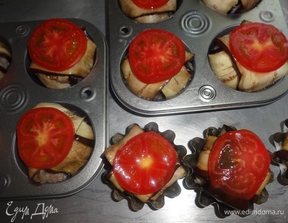 Смазать баклажаны в формочках остатками яйца и выложить на них кружки помидоров.