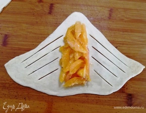По центру треугольника выкладываем абрикосовую начинку, надрезаем тесто, как показано на фото.