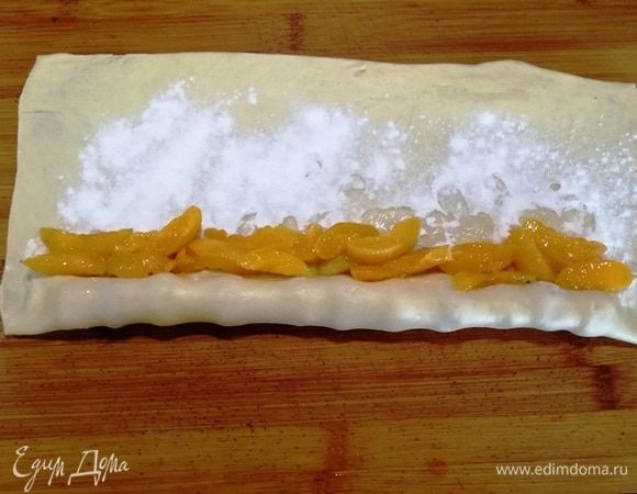 Делаем один оборот теста. Прижимаем боковые края, выкладываем абрикосы.