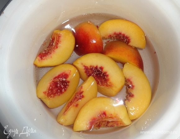 В кастрюлю налить воду, положить 2 ложки сахара, вскипятить. В кипящий сироп положить нарезанные персики. Бланшировать 2–3 мин. Огонь выключить, дать постоять персикам в сиропе минут 5. Затем вынуть. Сироп остудить до комнатной температуры. Он получится нежного розового цвета.