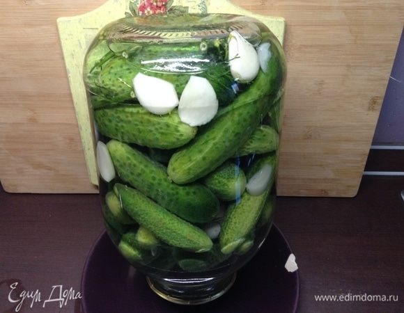 Огурчики пусть в воде полежат пару часов сперва. Банку над кипящей водяной баней простерилизовали. Укроп, чеснок (на зубчики разобрали и почистили) промыли и вместе с перцами (черный и душистый горошком) — в банку. Огурчики туда же сложили плотненько.