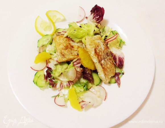 Насыпать салат горкой на тарелку, сверху положить кусочки рыбы, оформить дольками лимона и апельсина.