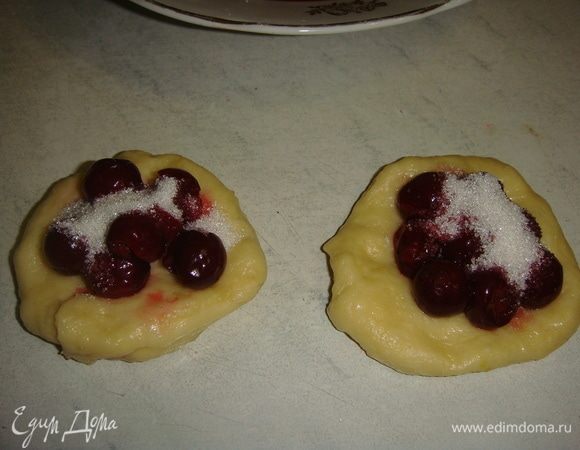 Берем немного теста и формируем лепешку, на середину выкладываем вишню, посыпаем сахаром, защипываем края и формируем пирожок.