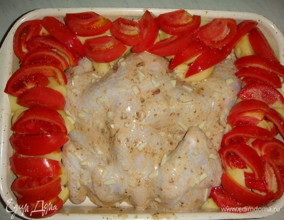 Помидоры тоже режем дольками и выкладываем поверх картофеля, солим. Чеснок мелко режем и посыпаем курицу. Форму накрываем фольгой и ставим в разогретую до 200°C духовку. Через 40 минут снимаем фольгу и посыпаем натертым сыром. Запекаем еще минут 20–30.