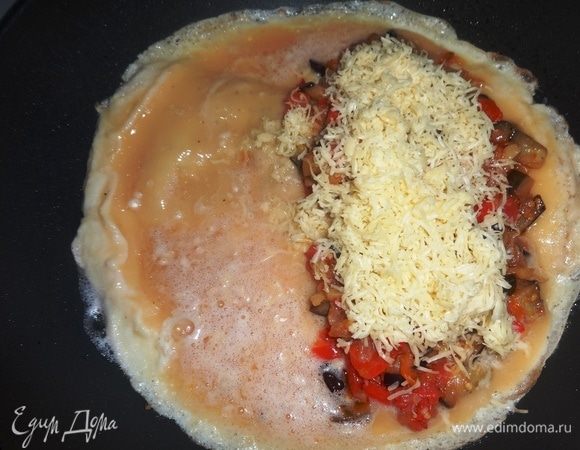 В сковороду налить порцию масла для омлета, разогреть. Вылить яичную смесь в сковороду, жарить на несильном огне несколько минут, чтобы хорошо схватился низ омлета. На одну половину омлета выложить начинку, посыпать ее сыром. Продолжать жарить еще пару минут.