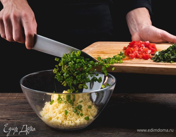 Смешайте в глубокой миске пропаренный кускус, томаты и зелень.