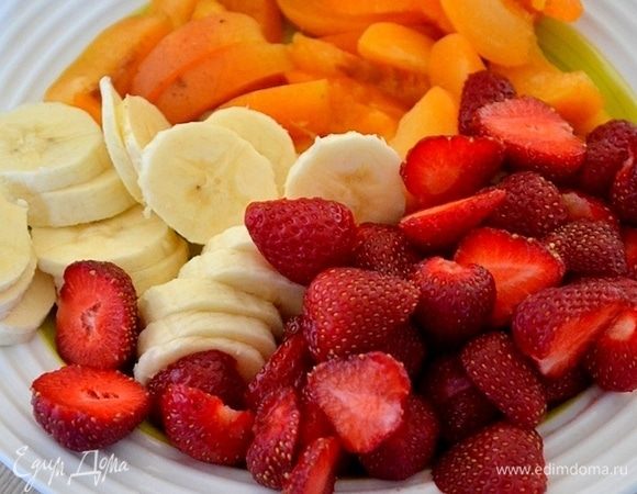 Банан нарезаем тонкими кружками, абрикосы — ломтиками, клубнику — пополам.